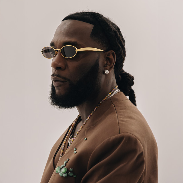 Burna Boy i brun dress og gullinnfattede solbriller