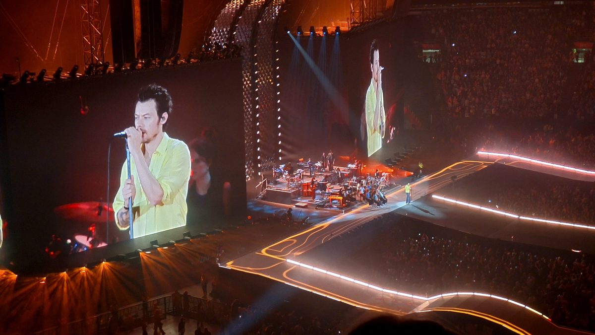 Harry Styles på storskjermene over scenen i Johan Cruijff ArenA, med publikum rundt de opplyste gangbroene