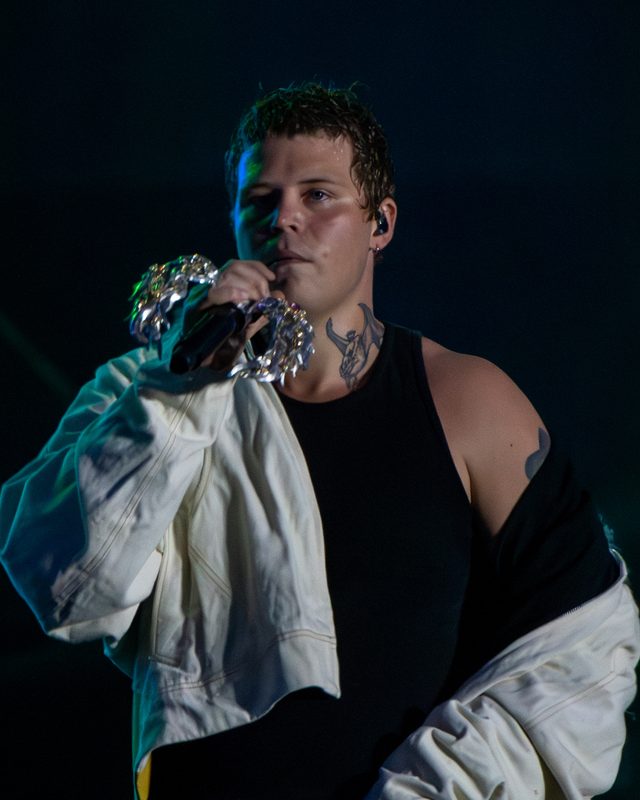 Yung Lean synger i mikrofonen i svart singlet og hvit jakke på scenen under Clout Festival i 2024