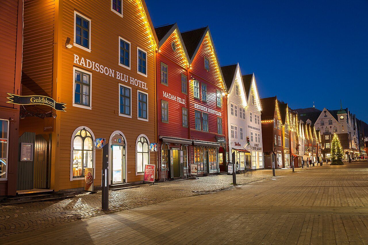 Bryggen i Bergen opplyst om natten, med de hanseatiske trehusene speilet i Vågen