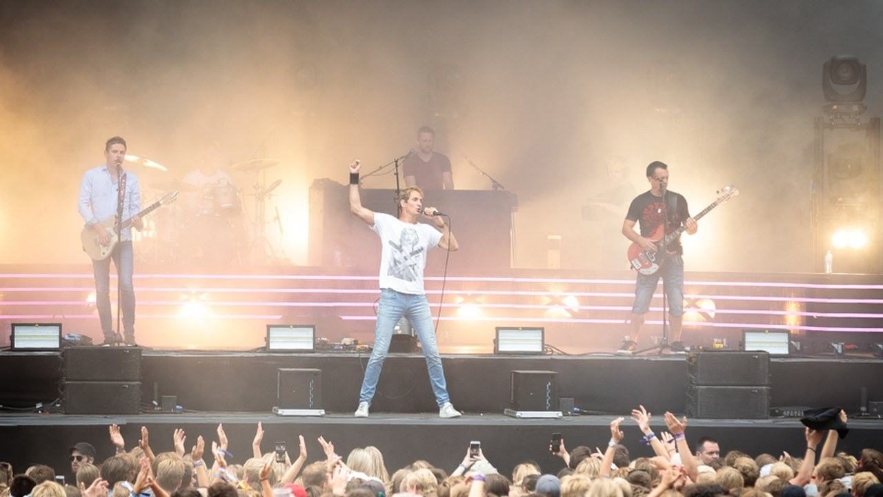 Postgirobygget på en utendørs festivalscene, med vokalisten fremst med hevet arm og publikumshender nederst i bildet