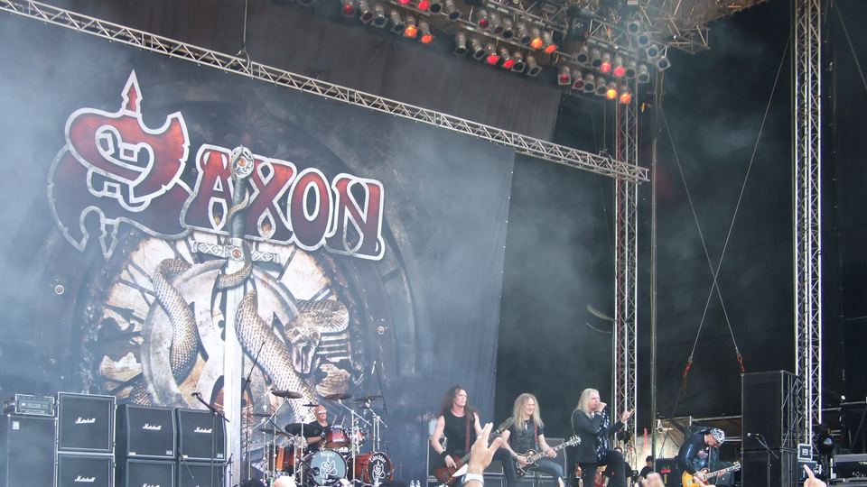 Saxon på scenen under Sofia Rocks Fest i 2011, foran bandets logobanner og med hender i været fra publikum